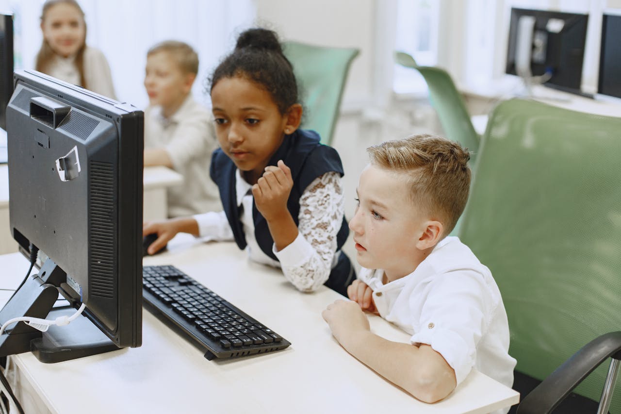 Children of diverse backgrounds learning and interacting with computers in a modern classroom.